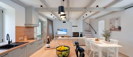 A modern kitchen with a wooden island, white cabinetry, and a dining area with white chairs and a table.