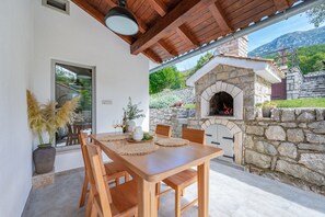 A dining area with a stone fireplace, wooden table, and chairs.