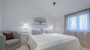 Een slaapkamer met een bed, nachtkastjes, een stoel en een wandlamp.