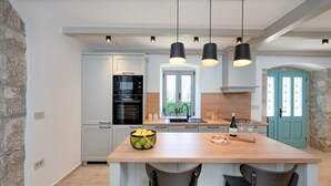Een moderne keuken met een centraal eiland, zwarte hanglampen en een stenen wand.