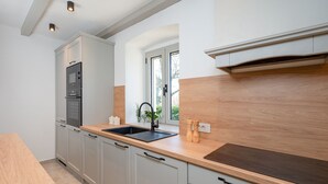Een moderne keuken met inbouwapparatuur, een houten aanrechtblad en een raam dat voor natuurlijk licht zorgt.