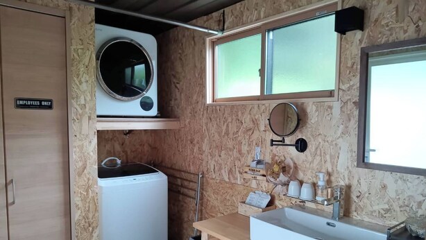 A compact kitchen with a built-in washing machine, a small sink, and a mirror.