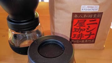 Un moulin à café et un sac en papier avec du texte en japonais, posés sur une table en bois.
