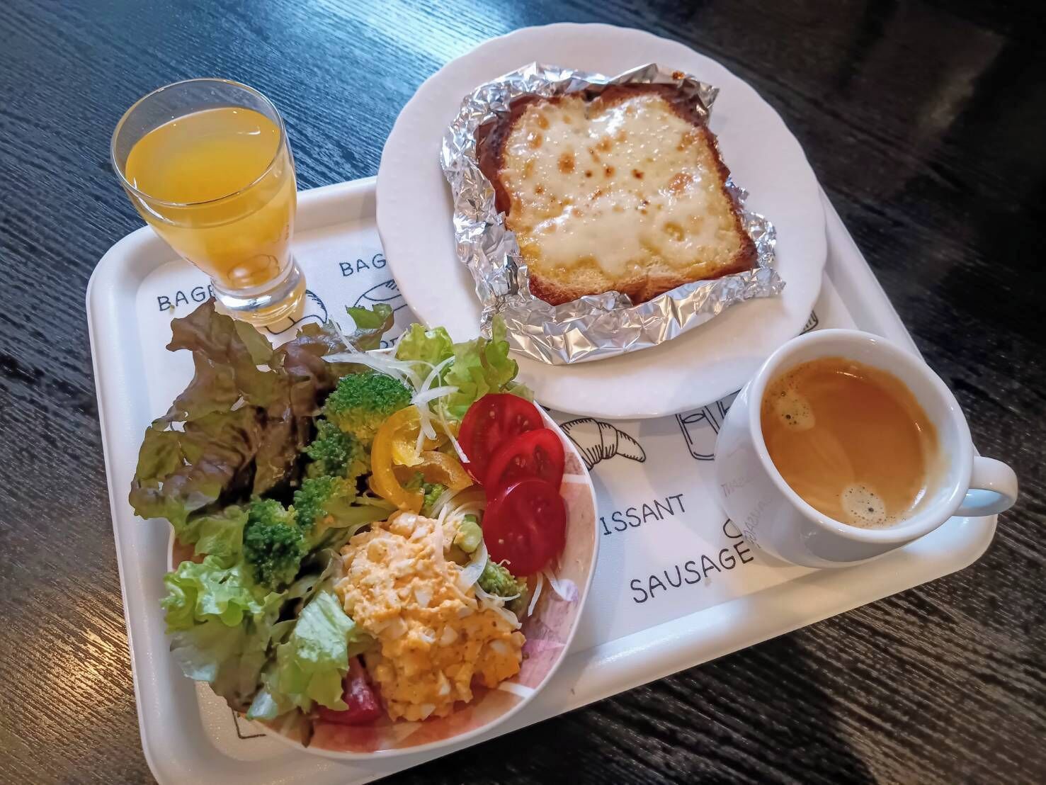 A meal tray with a salad, a baked dish, and a cup of tea.