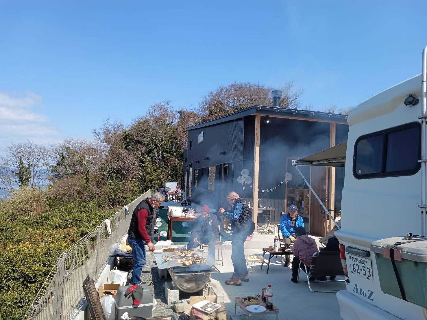 Ein Wohnmobil steht neben einem modernen Gebäude mit Grillmöglichkeit.