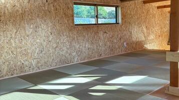 Una habitación con vigas de madera, un ventanal y esteras de tatami.