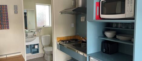 A compact kitchen with a microwave, sink, and a small refrigerator.