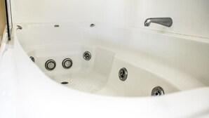 Eine weiße Badewanne mit einem Wasserhahn und drei Abläufen.