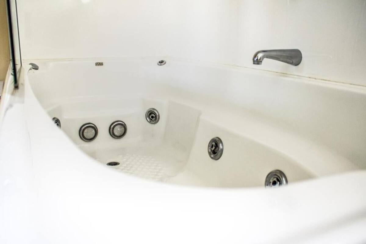 A white bathtub with a single faucet and three drain holes.