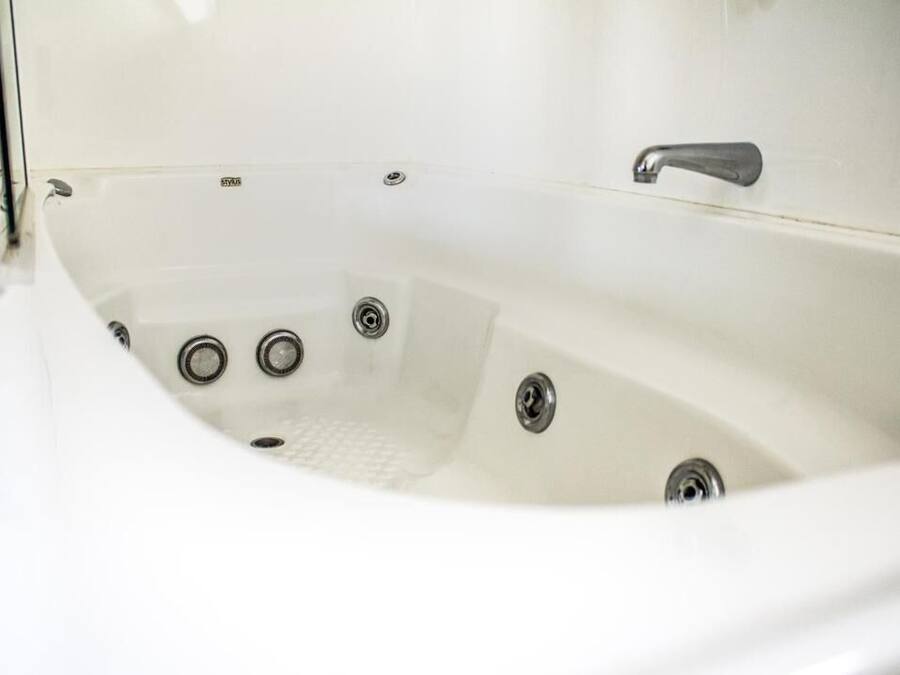 Una bañera blanca con un solo grifo y tres desagües.