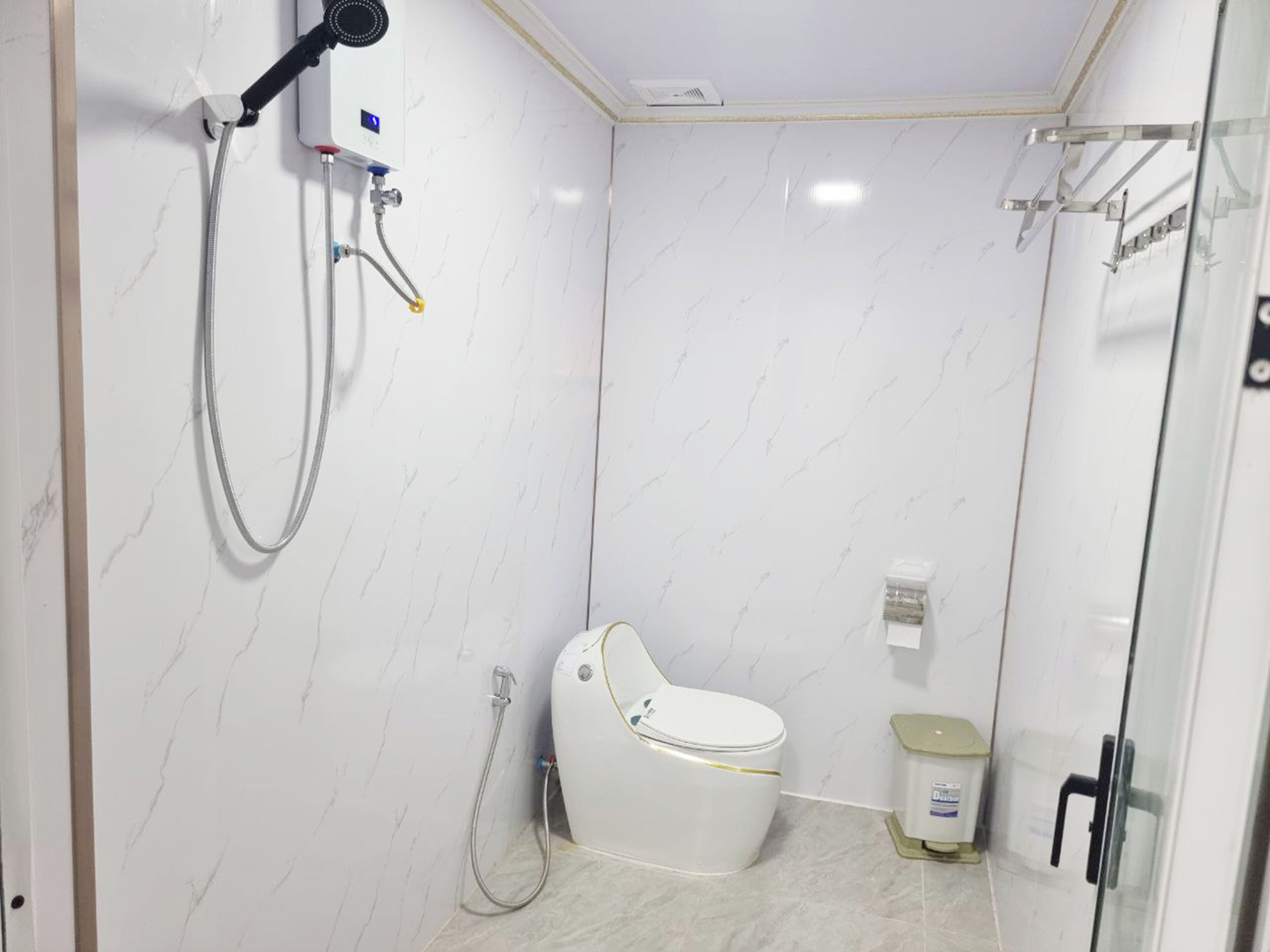 Un baño moderno con inodoro blanco, cabina de ducha y mampara de vidrio.
