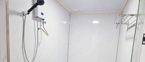 Un baño moderno con inodoro blanco, cabina de ducha y mampara de vidrio.