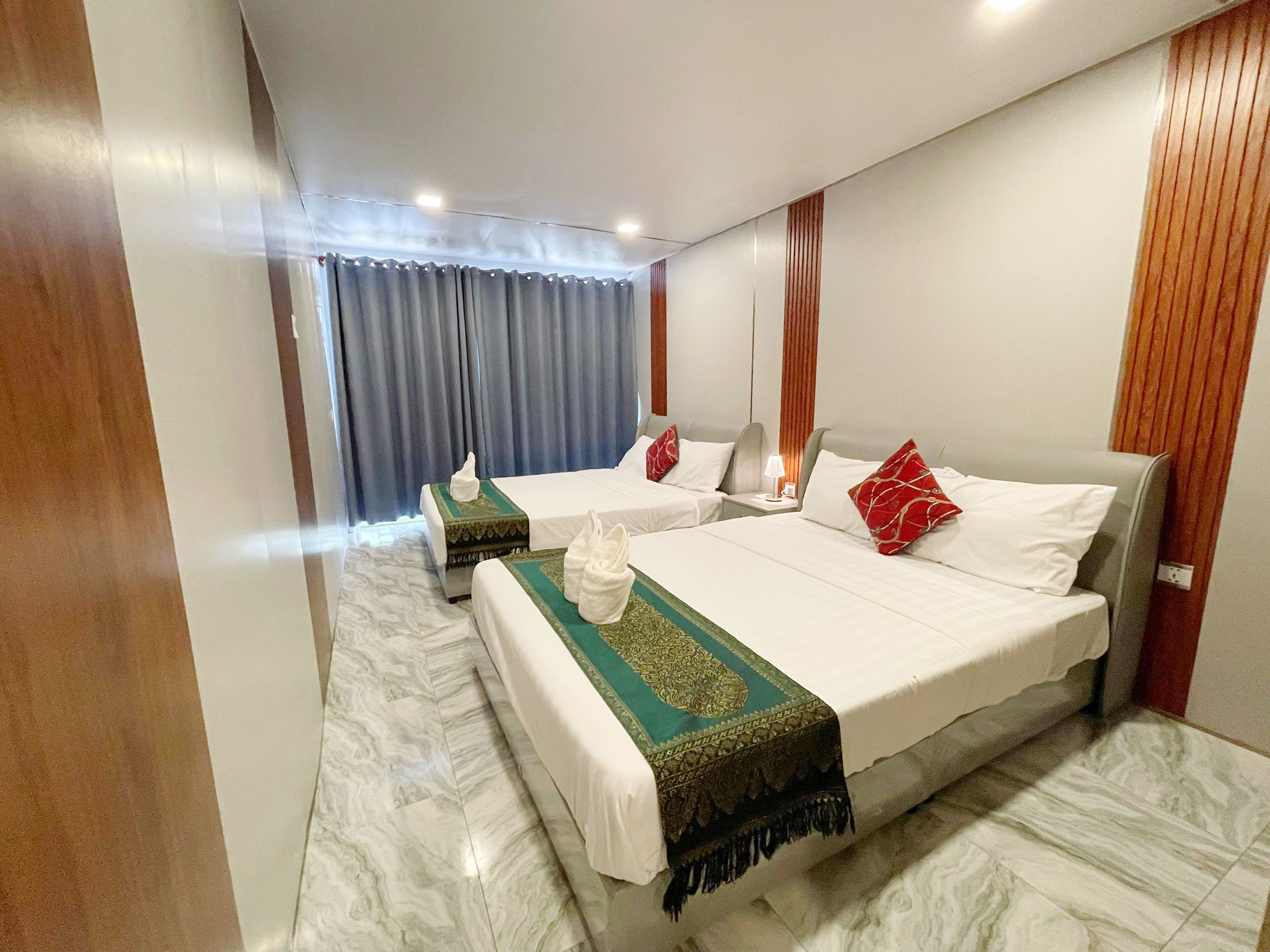 A hotel room with two beds, a marble floor, and a curtain.