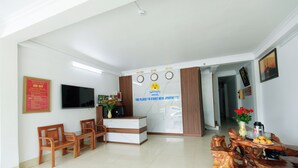 A hotel reception area with a reception desk, seating area, and a dining table with fruit. - Sapa Happy Hotel (Sa Pa)