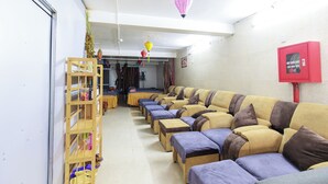 A hotel lobby with a row of sofas and chairs, a wooden shelf unit, and hanging lanterns. - Sapa Happy Hotel (Sa Pa)