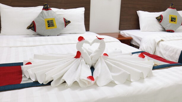 A hotel room with neatly made beds, each with white linens and decorative pillows. - Sapa Happy Hotel (Sa Pa)