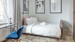 Een slaapkamer met een bed, een bureau, een stoel en drie afbeeldingen in lijsten aan de muur.