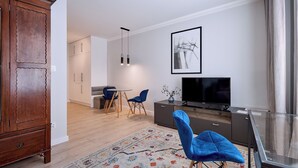 Een moderne woonkamer met een houten kast, een televisie, een glazen tafel en een blauwe stoel.