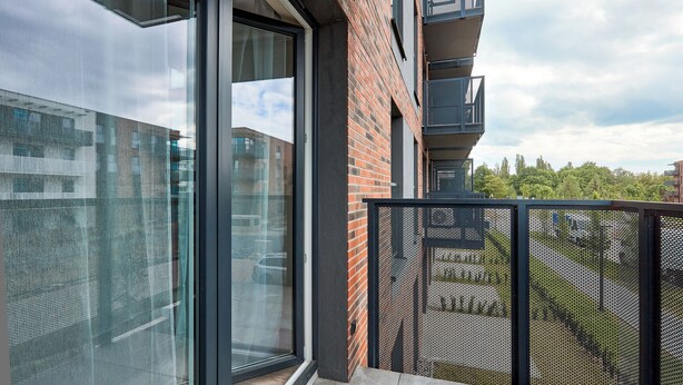 Un bâtiment moderne doté de grandes fenêtres en verre, d’une façade en briques et d’une balustrade en métal.
