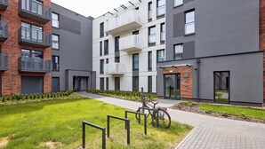 Un immeuble d’appartements moderne, doté de balcons, avec un vélo garé à l’extérieur et une pelouse bien entretenue.
