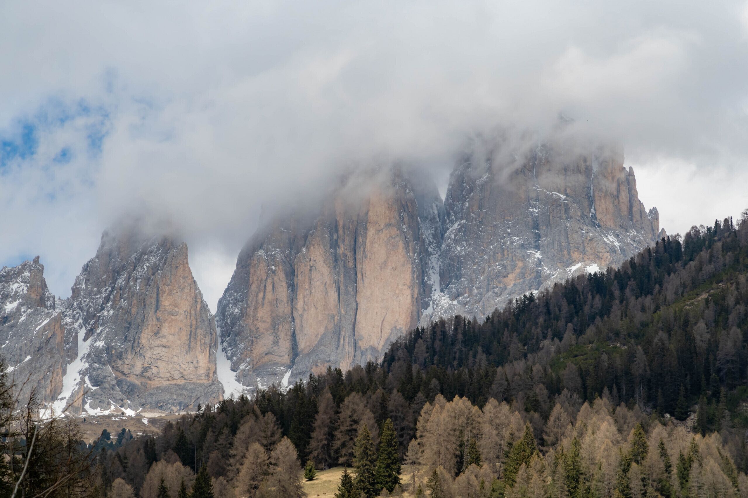 Een bergachtig landschap met torenhoge rotsformaties, deels verborgen door wolken.