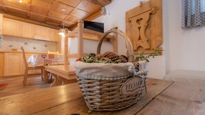 Un panier en osier avec une étiquette portant l’inscription « HOME » est posé sur une table en bois dans une cuisine dotée de meubles en bois et d’un luminaire suspendu.