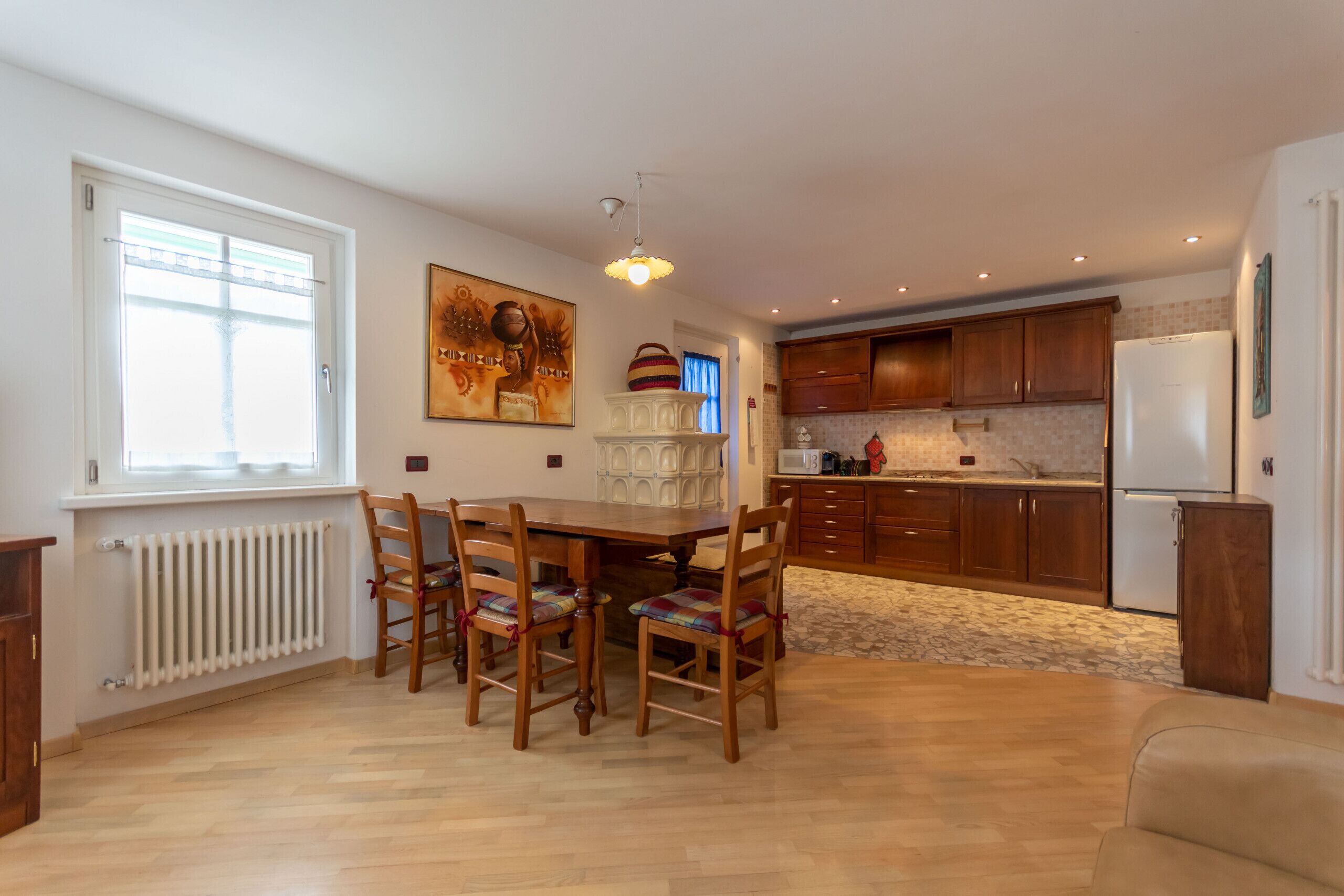 Een moderne keuken met houten kastjes, een witte koelkast en een eethoek met een houten tafel en stoelen.