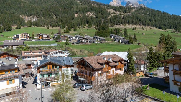 Un pueblo de montaña con casas de madera tradicionales, una plaza central y vistas al bosque y las montañas circundantes.