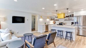 Una cocina moderna con armarios blancos, electrodomésticos de acero inoxidable y una isla central con taburetes de bar.