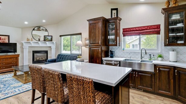 Una cocina moderna con una isla central, armarios de madera oscura y una chimenea.