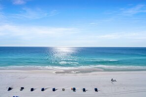 A beach with rows of sun loungers and a clear view of the ocean.