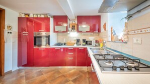 A modern kitchen with red cabinets, stainless steel appliances, and a gas stove.