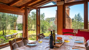 A dining area with a table set for two, a bottle of olive oil, and a bowl of olives.