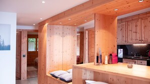 A modern kitchen with wooden cabinetry, a central island with bar stools, and a built-in bench with cushions.