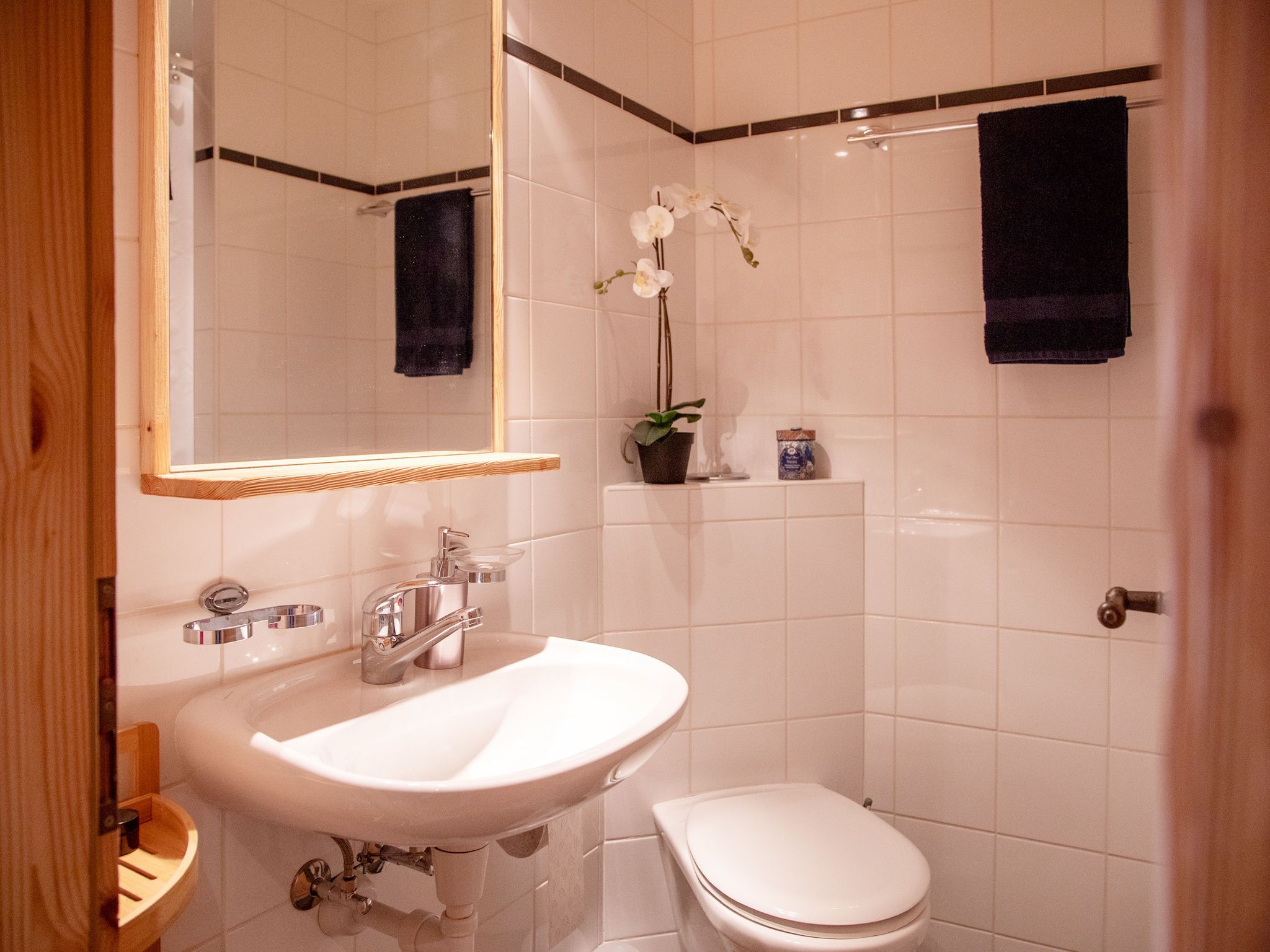 Une salle de bain avec un lavabo blanc, des toilettes, un miroir et un espace douche.