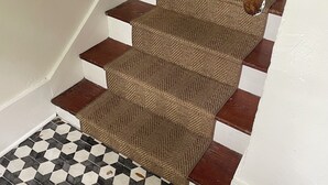 A staircase with a patterned carpet and a checkered floor.