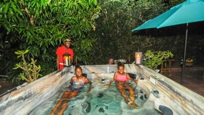 Un jacuzzi con dos personas, rodeado de exuberante vegetación.