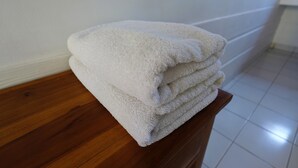 Un montón de toallas blancas sobre una superficie de madera en una habitación con paredes blancas y suelo de baldosas.