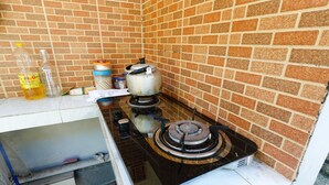 Una cocina con estufa a gas, una olla en la hornilla y diversos utensilios de cocina sobre la encimera.