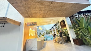 Een receptie met een houten plafond, een marmeren balie en potplanten.