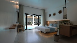 Een moderne hotelkamer met een bed, een bureau, een stoel, een potplant en uitzicht op het buitengebied.