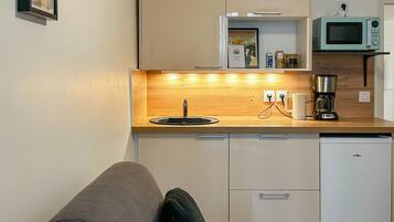 Een kleine keuken met een houten aanrecht, een spoelbak, een magnetron en een koffiezetapparaat.