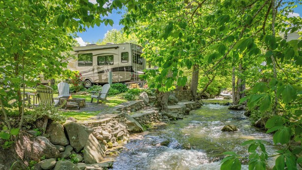 A campground with a river, a covered RV, and outdoor seating. - Luxury Creekside Retreat: RV in Gatlinburg,Tn (Gatlinburg)