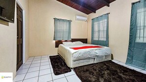 Un dormitorio con cama, ventana, puerta y suelo de baldosas.