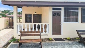Una casa de dos pisos con un porche cubierto, una puerta principal y una ventana.