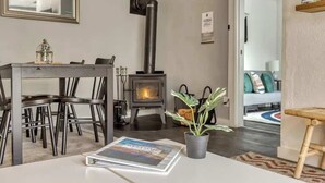 A modern living room with a fireplace, dining table, chairs, and a potted plant. - Riverbend Cabin Hot Tub, River Front Dog Friendly (Rhododendron)