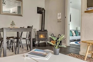 A modern living room with a fireplace, dining table, chairs, and a potted plant.
