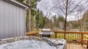 A hot tub on a wooden deck with a grill and a wooden fence in the background. - Riverbend Cabin Hot Tub, River Front Dog Friendly (Rhododendron)