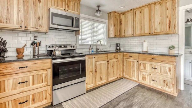 A kitchen with wooden cabinets, a microwave, stove, and a sink. - Riverbend Cabin Hot Tub, River Front Dog Friendly (Rhododendron)