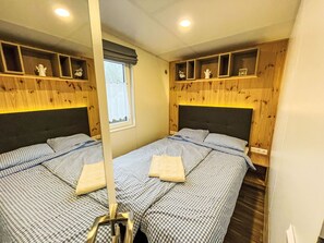 A room with two beds, wooden headboards, a window with curtains, and shelves with decorative items. - Tiny Haus Conny by Interhome (Wemding)